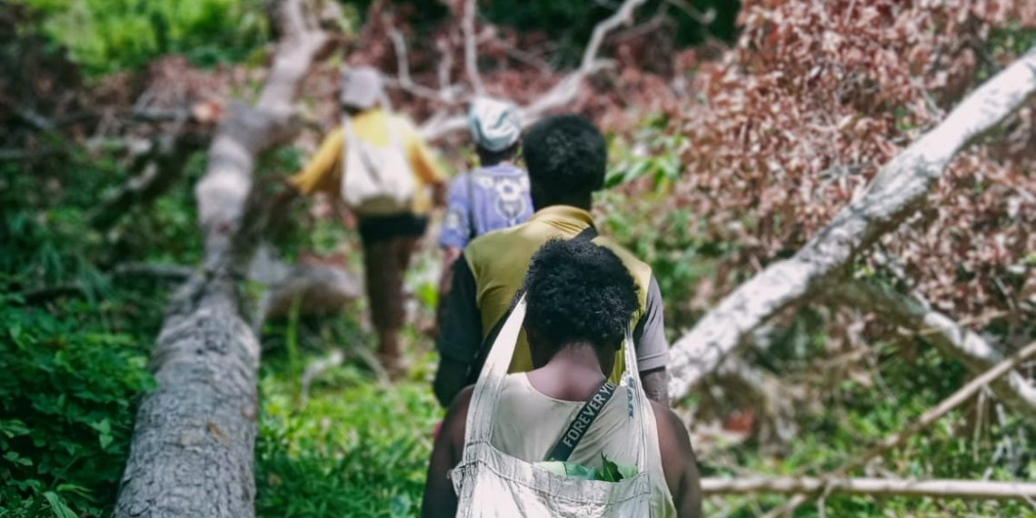Perempuan Marind saat bekerja dengan membawa karung.